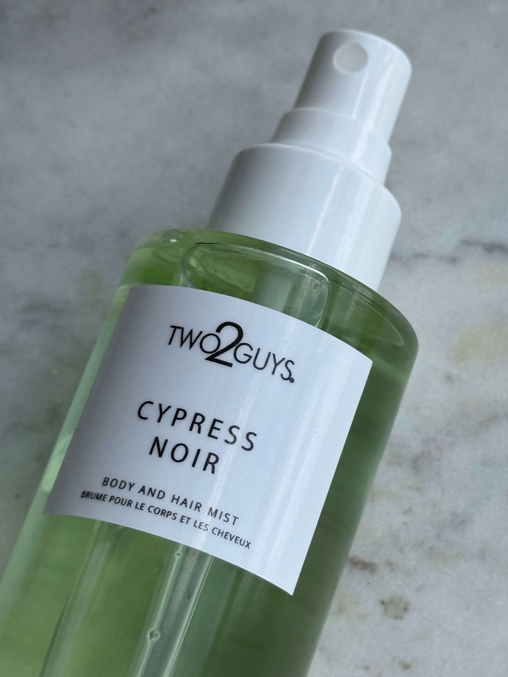 Two2Guys Cypress Noir body and hair mist bottle on a gray background with notes of rapefruit, cypress, cardamom, sandalwood, and musk