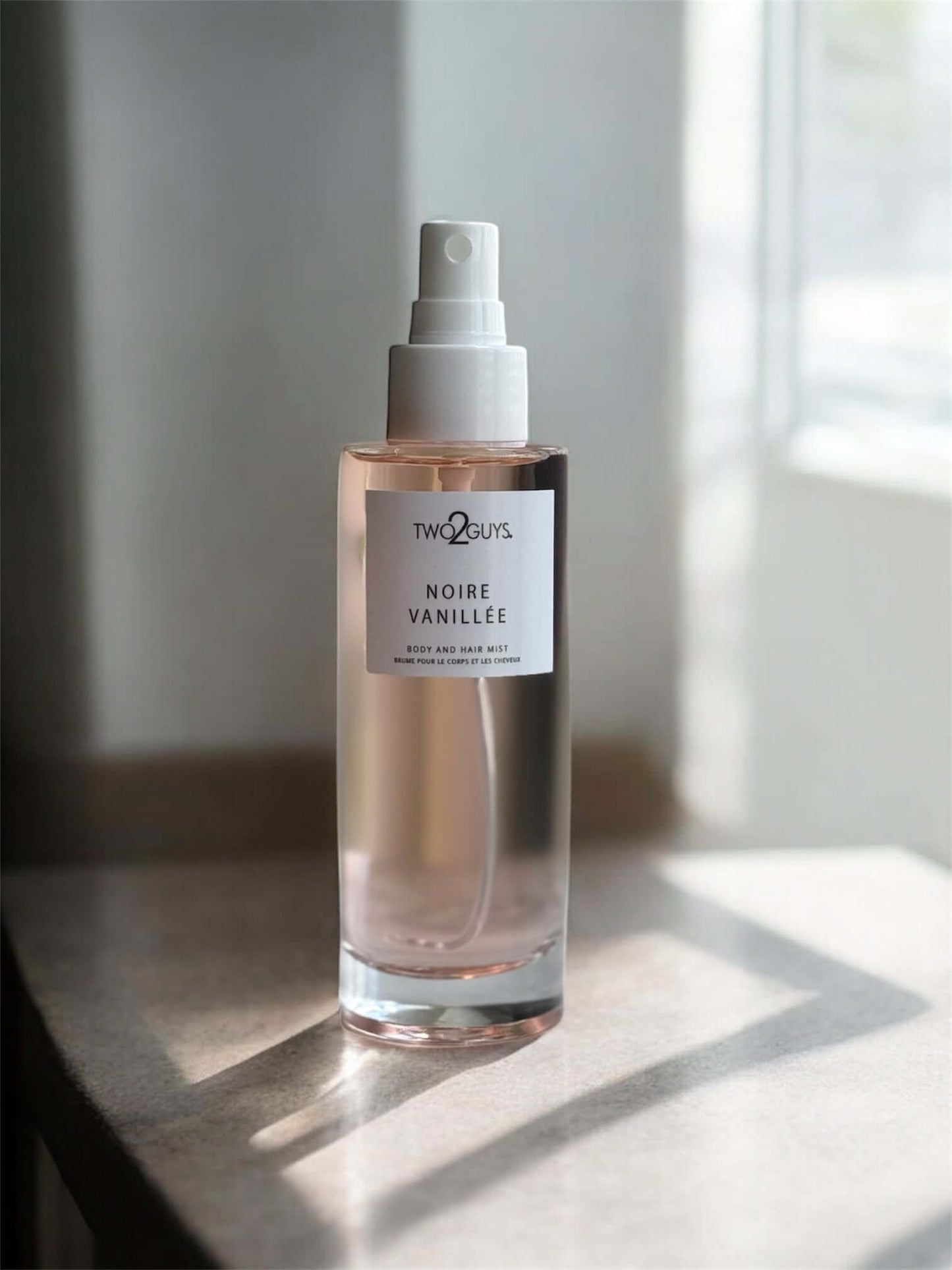 Noire Vanille body mist by TWO2GUYS on a light surface with a neutral background, notes of vanilla, jasmine, coffee, and patchouli