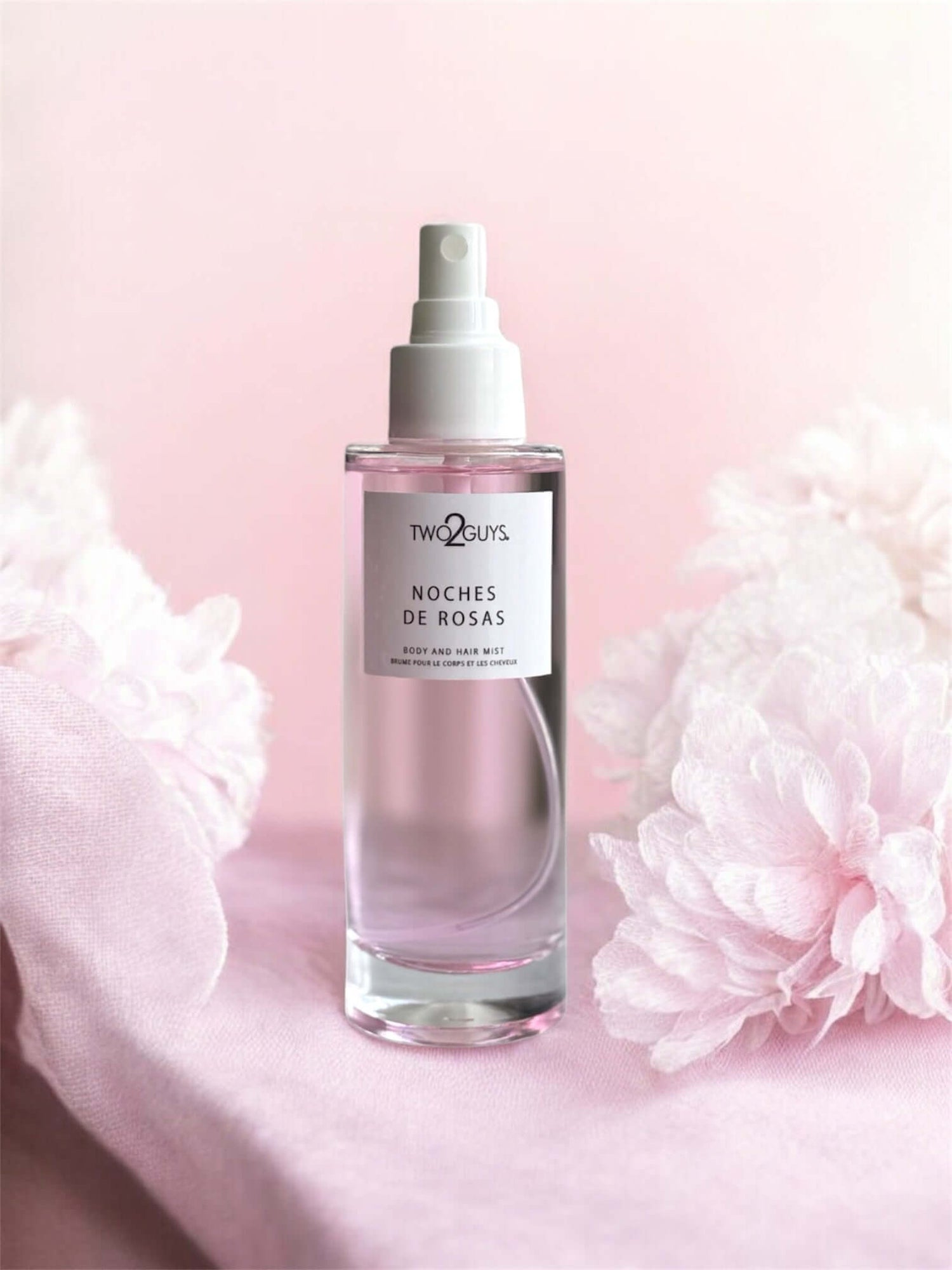 Perfume bottle labeled 'Noches de Rosas' with pink flowers on a light pink background, body and hair mist with rose, peony, and pink pepper notes