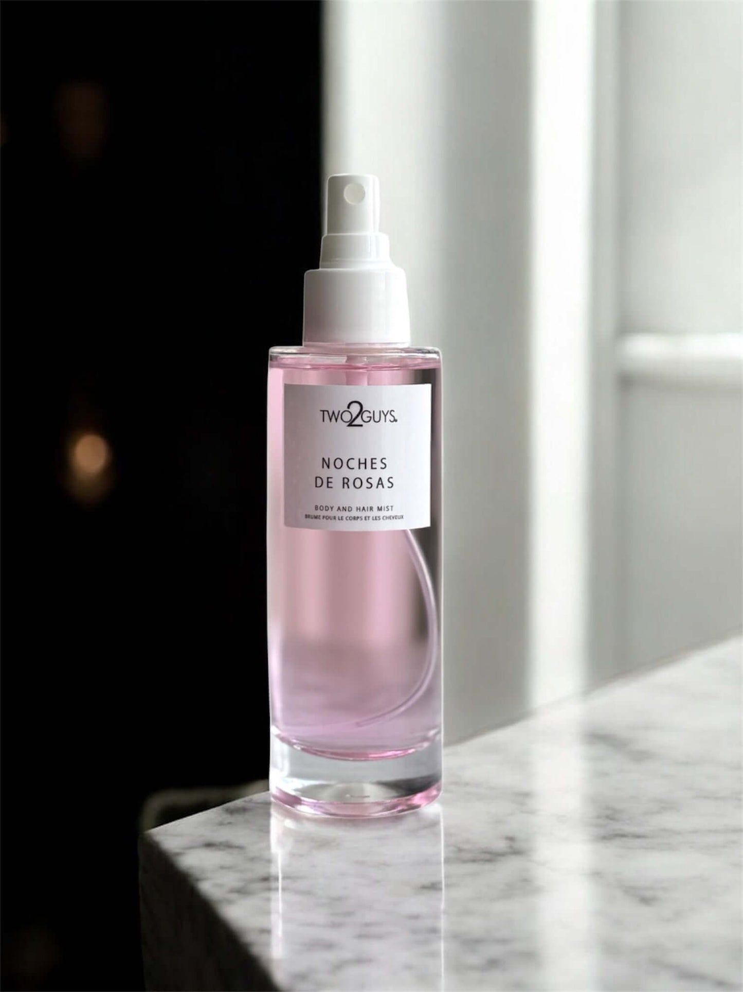 body and hair Mist noche de rosas on a marble surface with a blurred background
