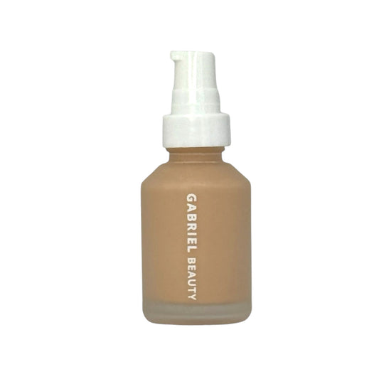 A pump bottle of Luminé Essence Liquid Foundation by Gabriel Beauty with a beige tint and white labeling.