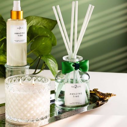 clear vintage glass and reed diffuser with a green bow and a room spray in a gold cap