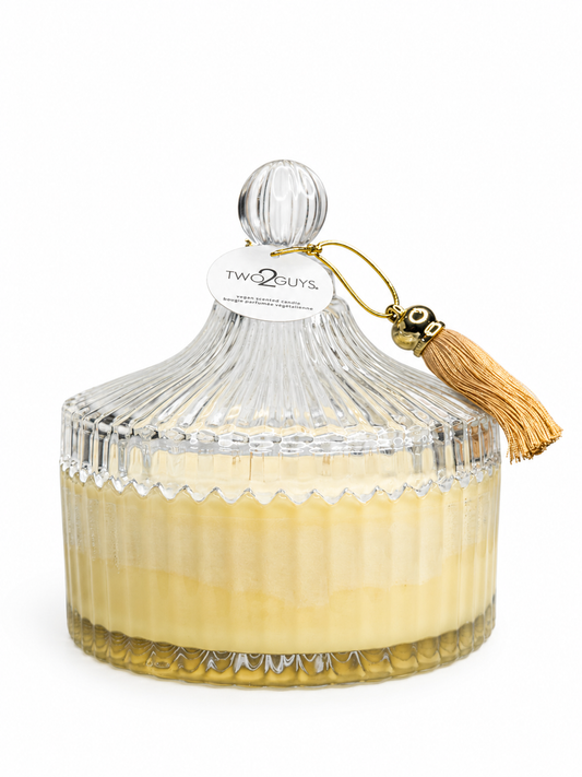 Decorative candle in a glass container with a tassel on a white background