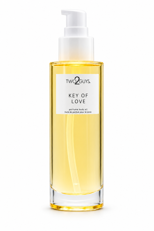 A bottle of Two2Guys Key of Love perfume body oil with a white pump dispenser and a white label, showing the golden-yellow oil inside, on a solid white background.