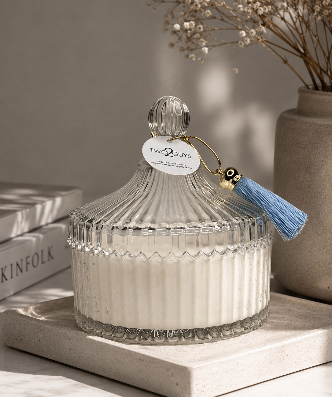 Decorative glass container with a tassel on a neutral background
