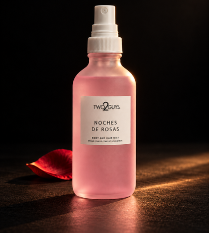 A pink spray bottle of Two Guys Noches de Rosas Body and Hair Mist, styled with a single red rose petal on a dark surface against a black background.